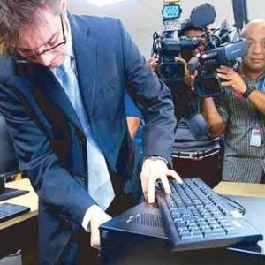 Cameras focus on Marlon Garcia of Smartmatic as he fiddles around with COMELEC equipment.